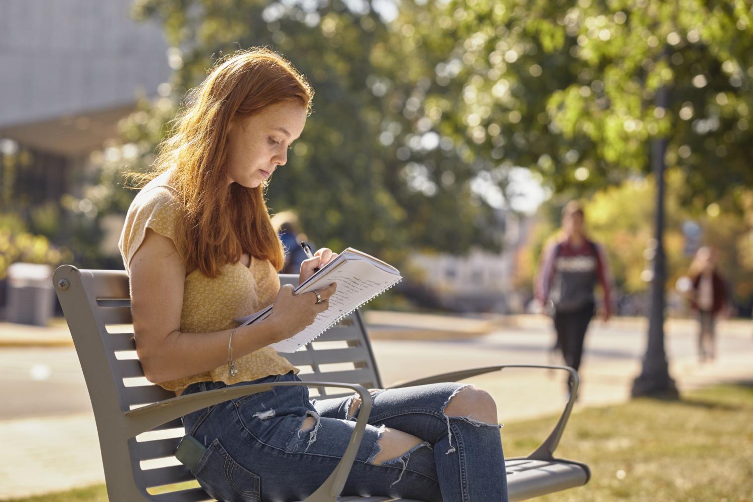 A <a href='http://rqxl.psozxd.com'>博彩网址大全</a> student reads on a bench along Campus Drive.